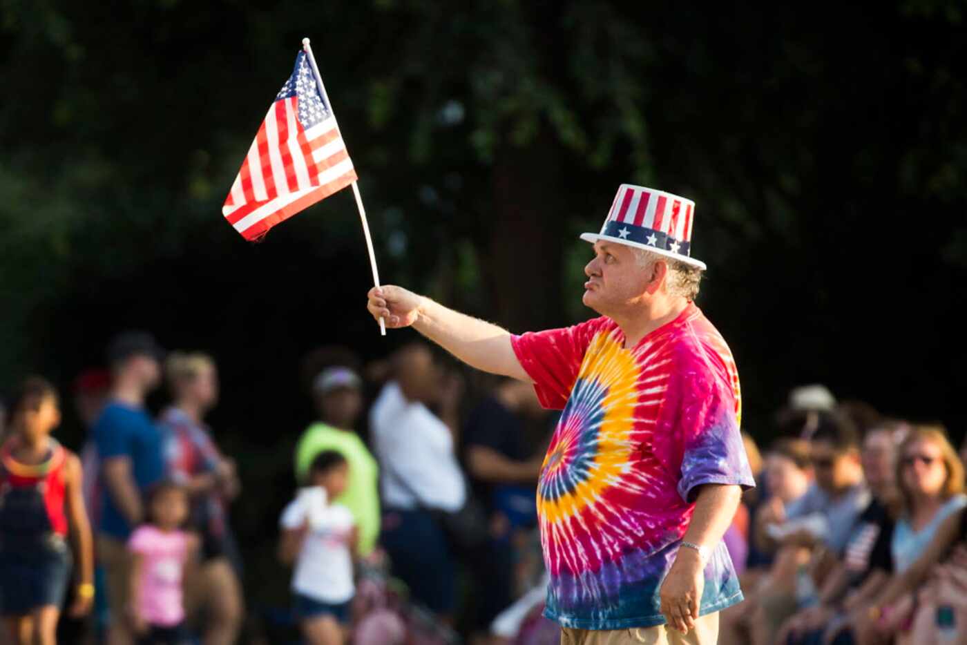Bob Crawford waves the flag while listening to the Dallas Winds perform in front of the Hall...