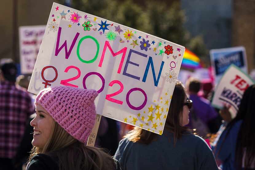 Participants in the 2020 Dallas Women's March walk along Canton Street on their way to a...
