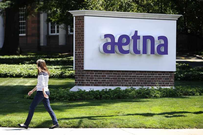 a pedestrian walks past a sign for health insurer Aetna Inc., at the company headquarters in...