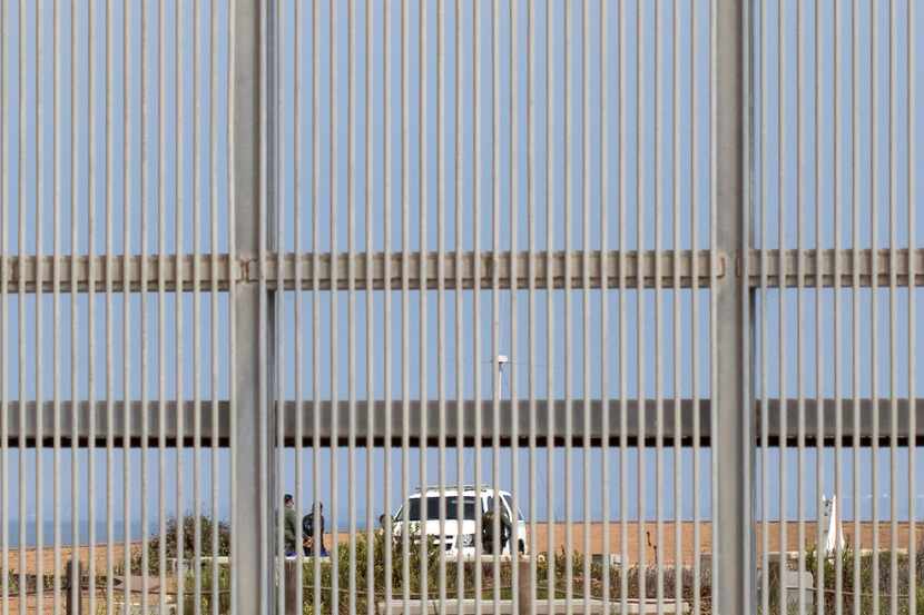 Border Patrol agents are seen through the border fence detaining a person  at the Border...