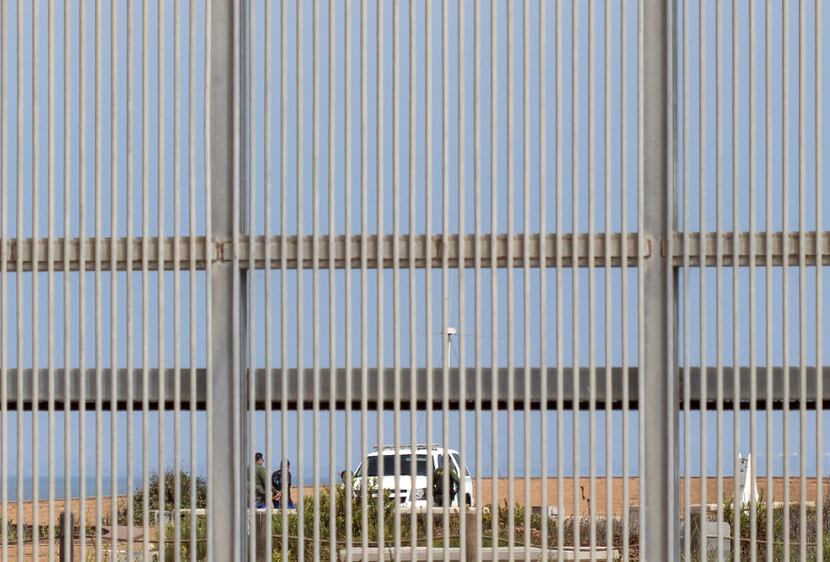 Border Patrol agents are seen through the border fence Border Field Park in Tijuana on Aug....
