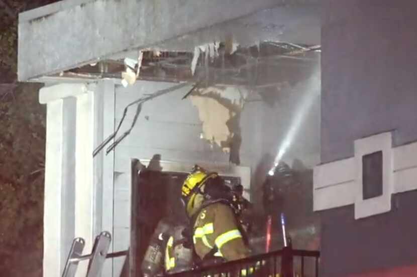 A Dallas firefighter shines a light into a damaged apartment after a fire broke out Monday...