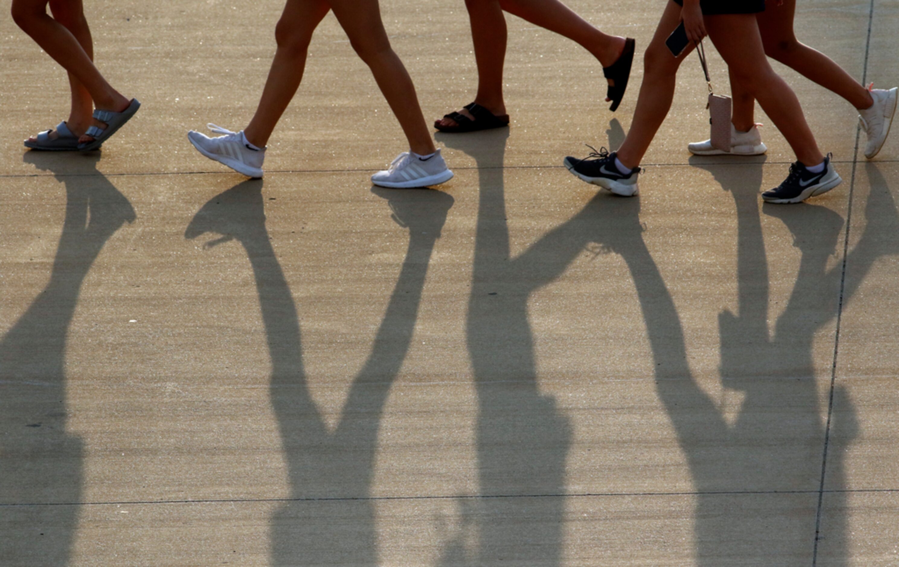 A group of Flower Mound fans walk across the parking lot toward one of the stadium entrances...