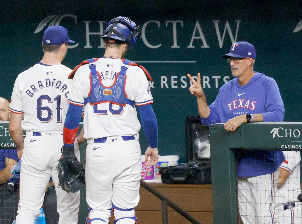 Texas Rangers pitching coach Mike Maddux, left, shows V-sign to Texas Rangers pitcher Cody...