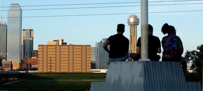 People at the Trinity Overlook Park watch as the sun sets on downtown Dallas and the former...