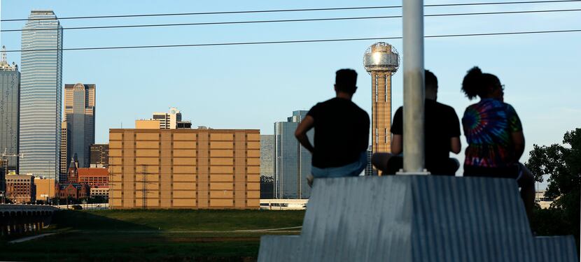 People at the Trinity Overlook Park watch as the sun sets on downtown Dallas and the former...