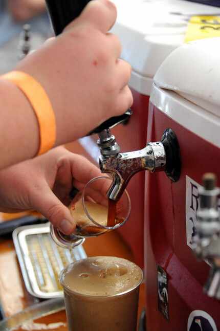 A worker for Rabbit Hole Brewing fills a glass with Rapture Fusion Brown Ale at an event...