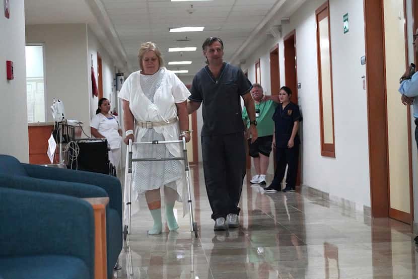 Physical therapist Carlos Bauque helps Donna Ferguson walk as she recuperates from her...