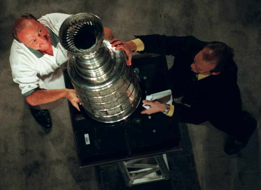 Stars owner Tom Hicks receives assistance from broadcaster Ralph Strangis to put the Stanley...