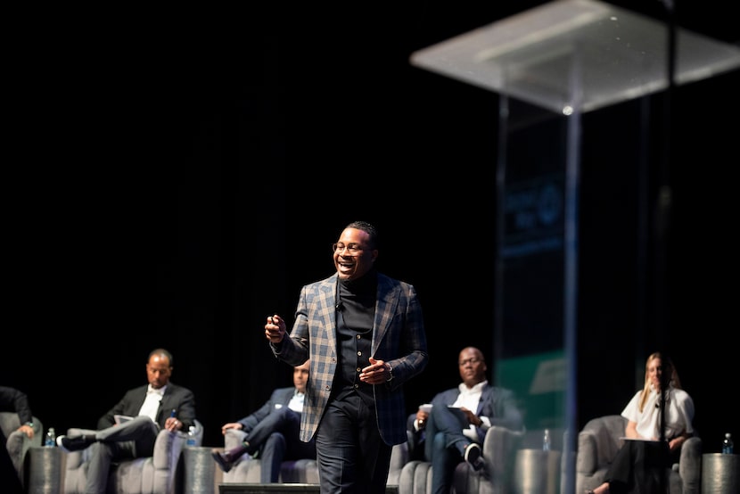 Man stands on stage speaking in front of a  seated panel of judges.