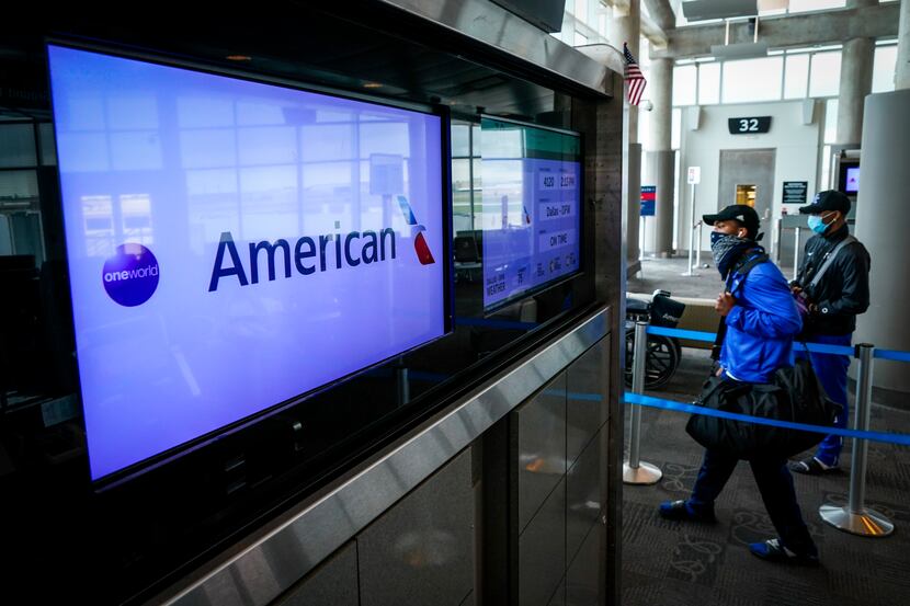 Passengers wearing face masks due to the new coronavirus board an American Airlines flight...