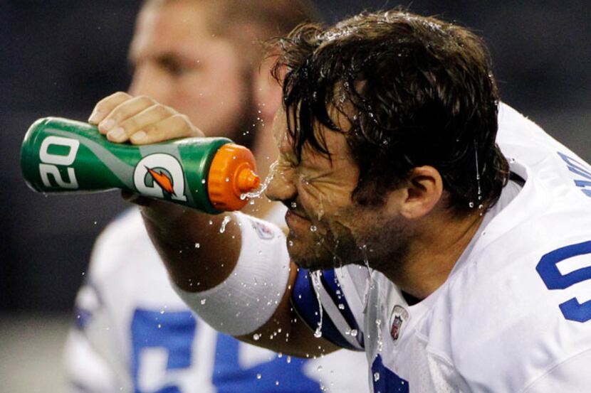 Dallas Cowboys quarterback Tony Romo sprays himself before an NFL football game against the...