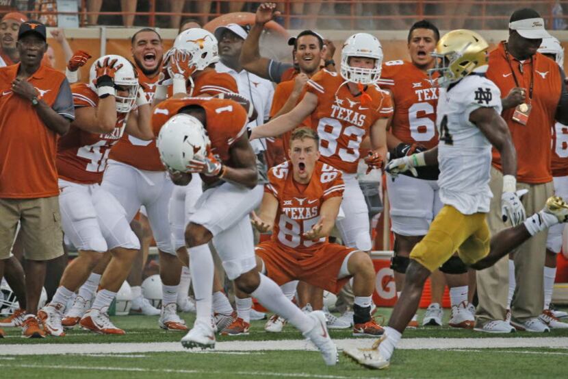 The Longhorns bench reacts as Texas wide receiver John Burt (1) can't get a handle on a...