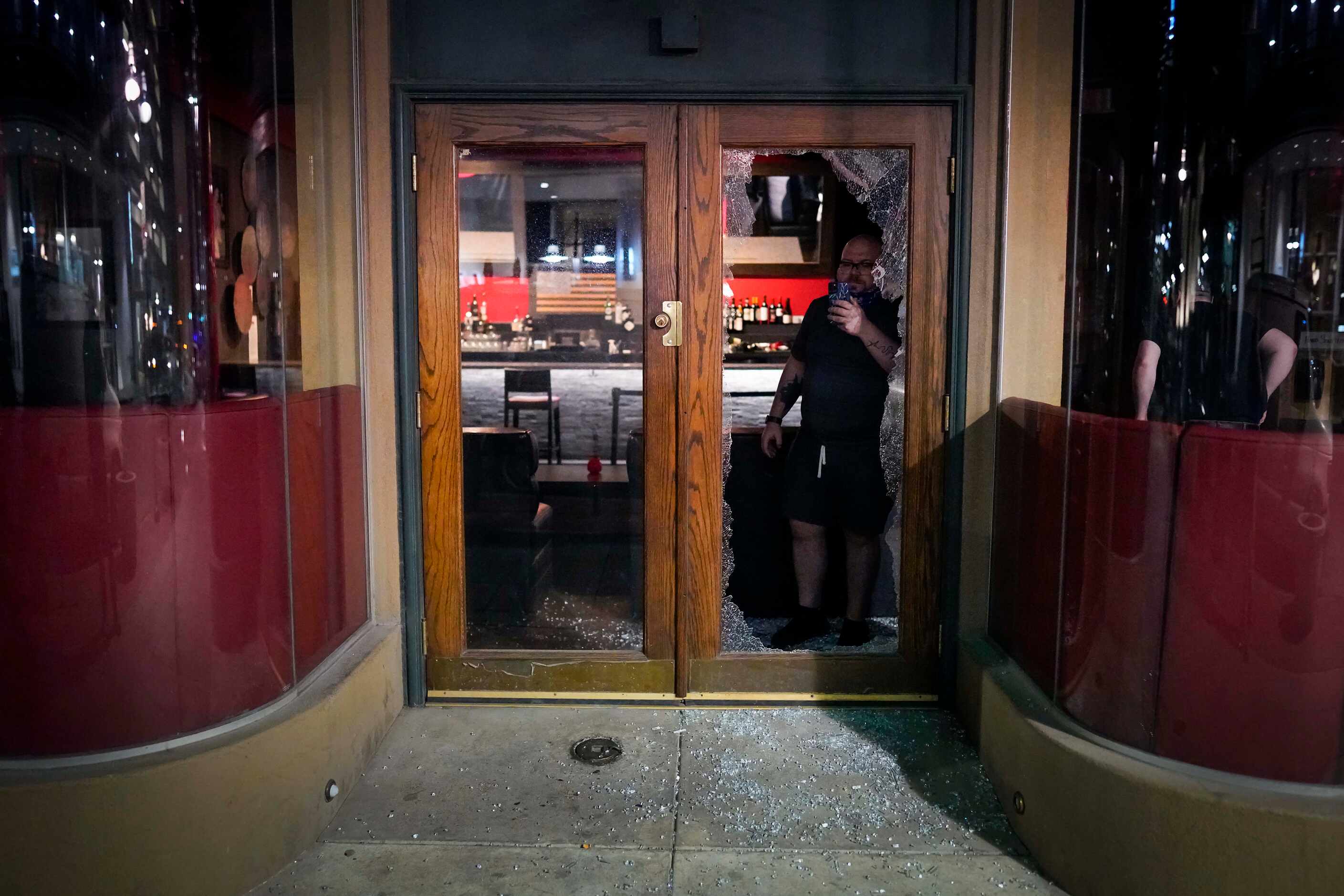 A man takes a photo through the broken glass doorway of Campisi's Restaurant downtown...