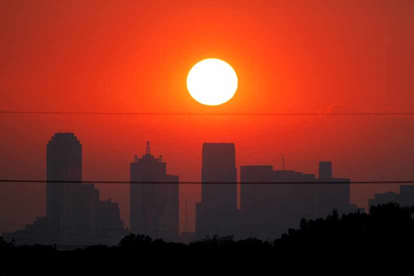 The sun sets beyond a humid city skyline following the storm that passed through in August 2011