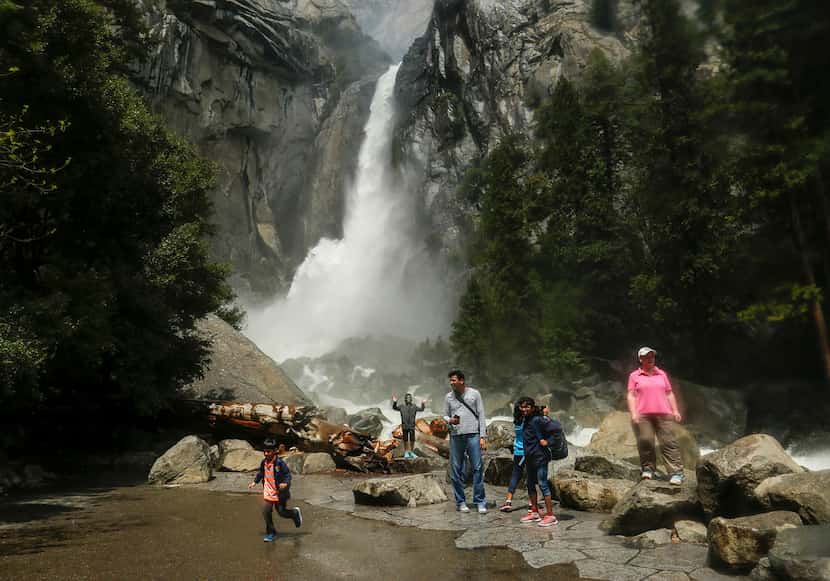 Visitors stand in a mist cloud while they snap pictures of the gushing Lower Yosemite Fall...