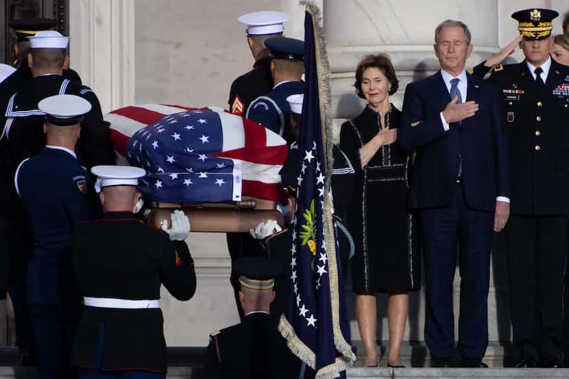 Former US President George W. Bush, and former First Lady Laura Bush, watch as the casket...