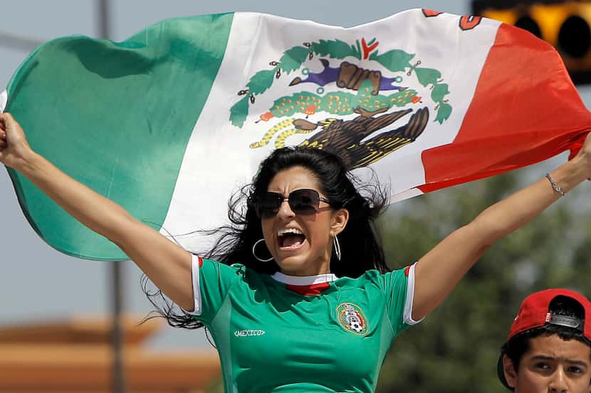 A Mexico soccer fan waves the Mexican flag before a soccer game against Brazil at Cowboys...
