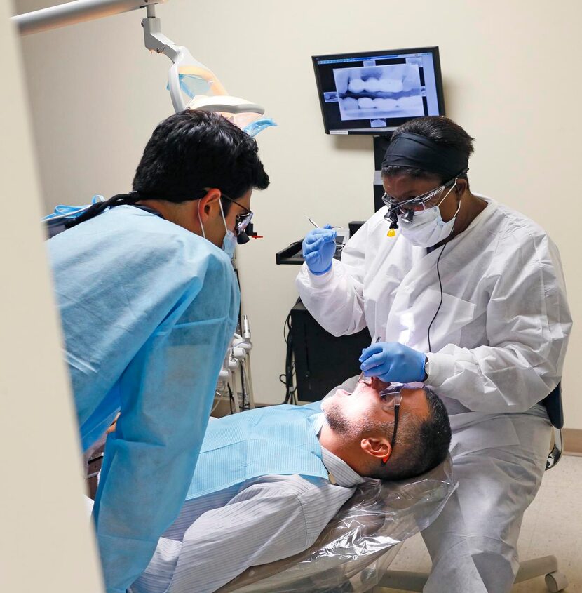 
Marie Latortue, faculty supervisor (right) works on Wameedh Sadoon's teeth as Neema Dad...