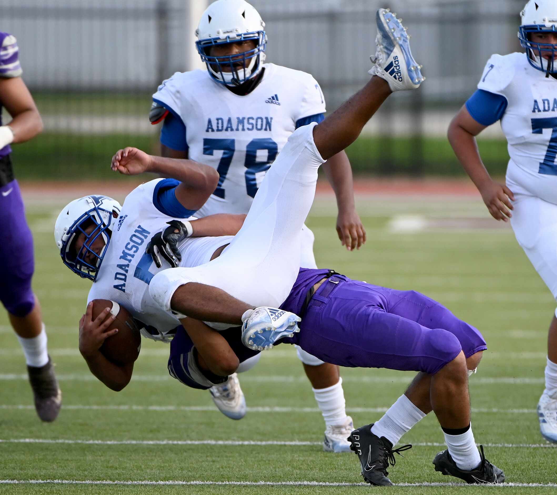Adamson's Daniel Garcia (5) is tackled by Sunset's Gustavo Rodriguez (16) in the first half...