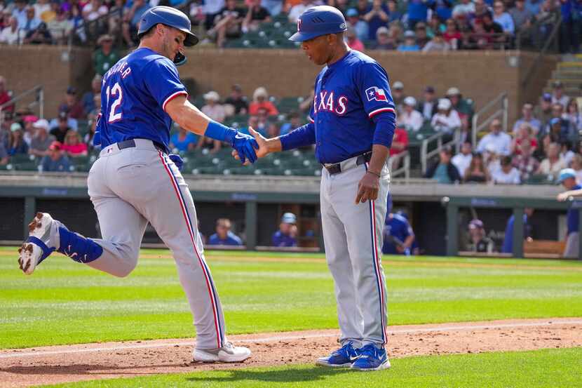 Texas Rangers designated hitter Andrew Knizner gets a hand from third base coach Tony...