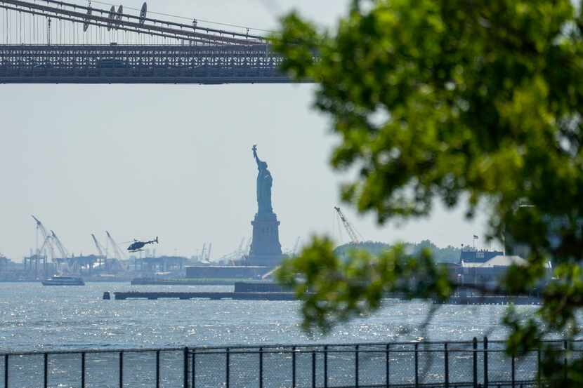 The Statue of Liberty and a helicopter lifting off in the haze from the Wall Street heliport...