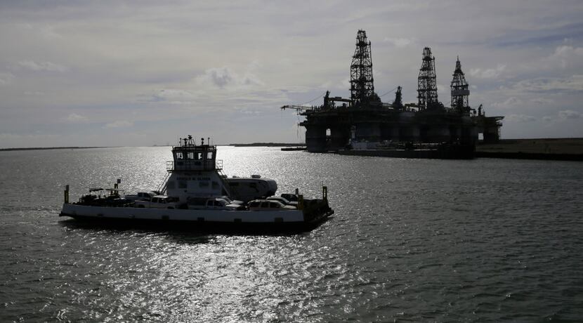 Vehicles and RVs pass parked oil platforms as they were ferried away from Port Aransas...