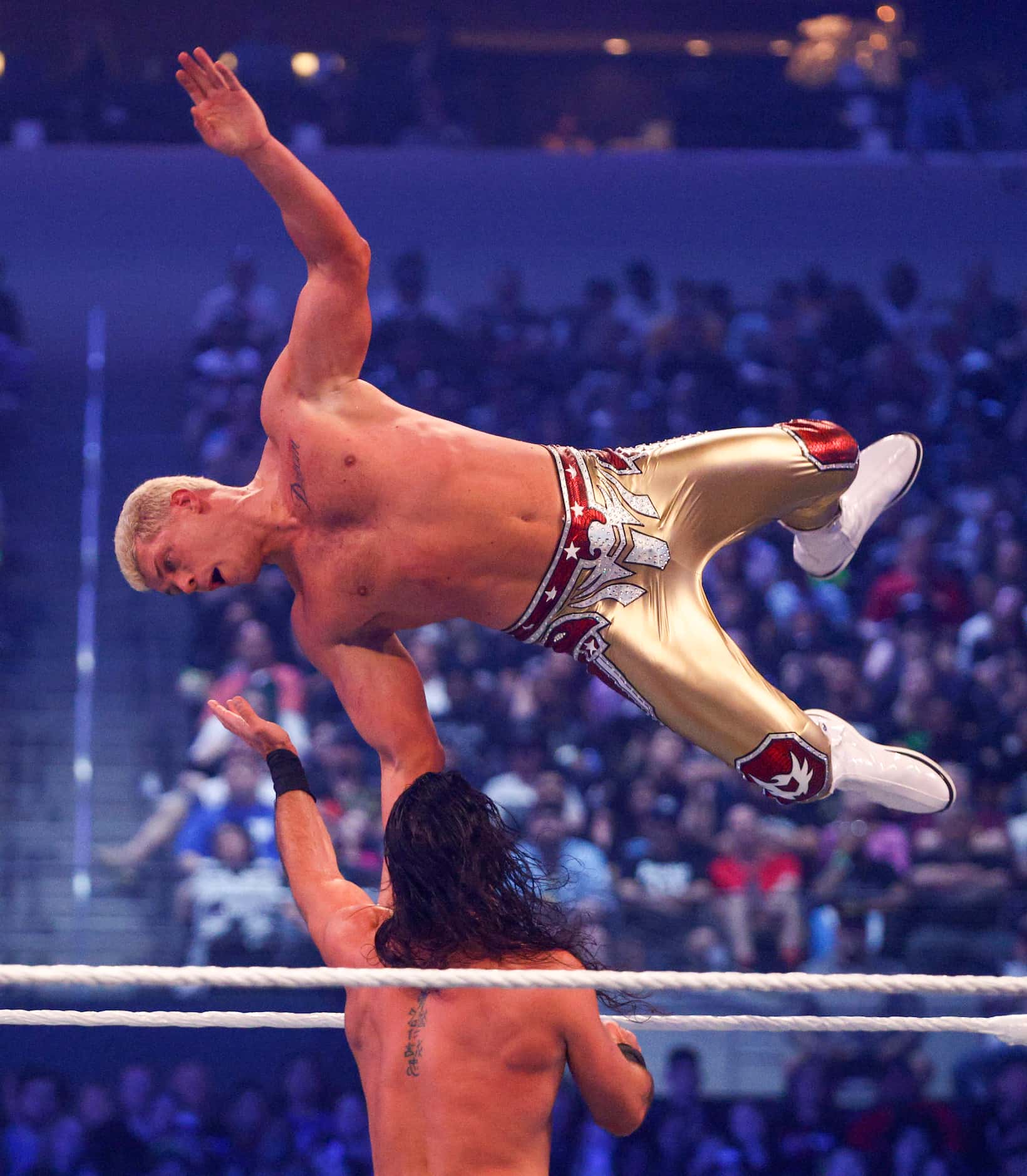 Cody Rhodes jumps onto Seth Rollins during a match at WrestleMania 38 at AT&T Stadium in...