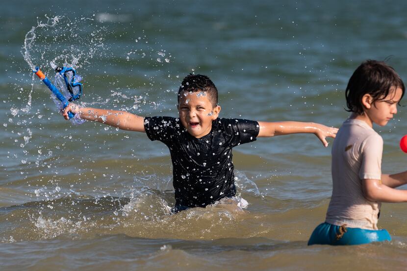 Sergio Linares, 7, of Dallas, splashes in a shallow area of Joe Pool Lake with his family at...