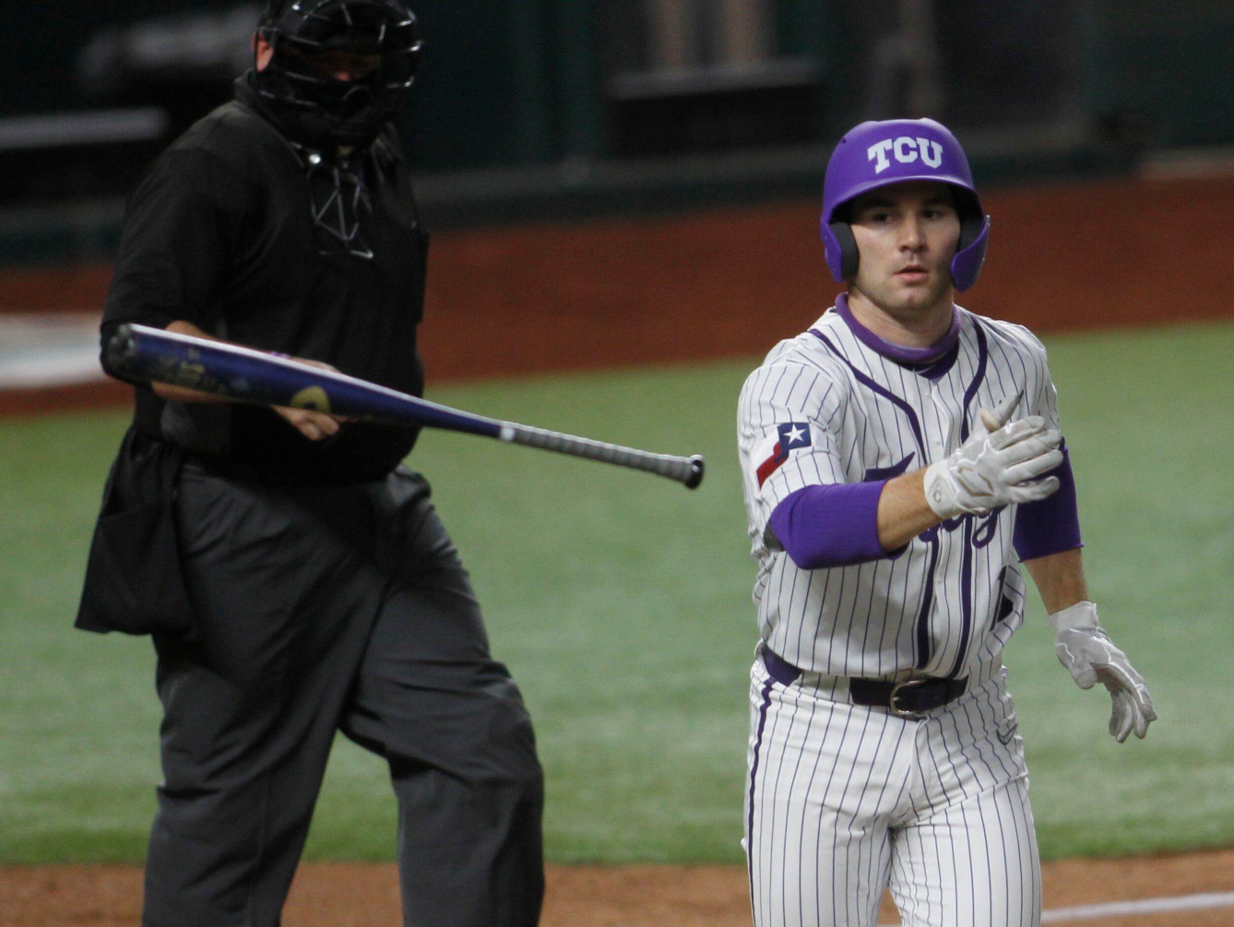 TCU catcher Zach Humphreys (10) tosses his bat and takes first base after being hit by a...