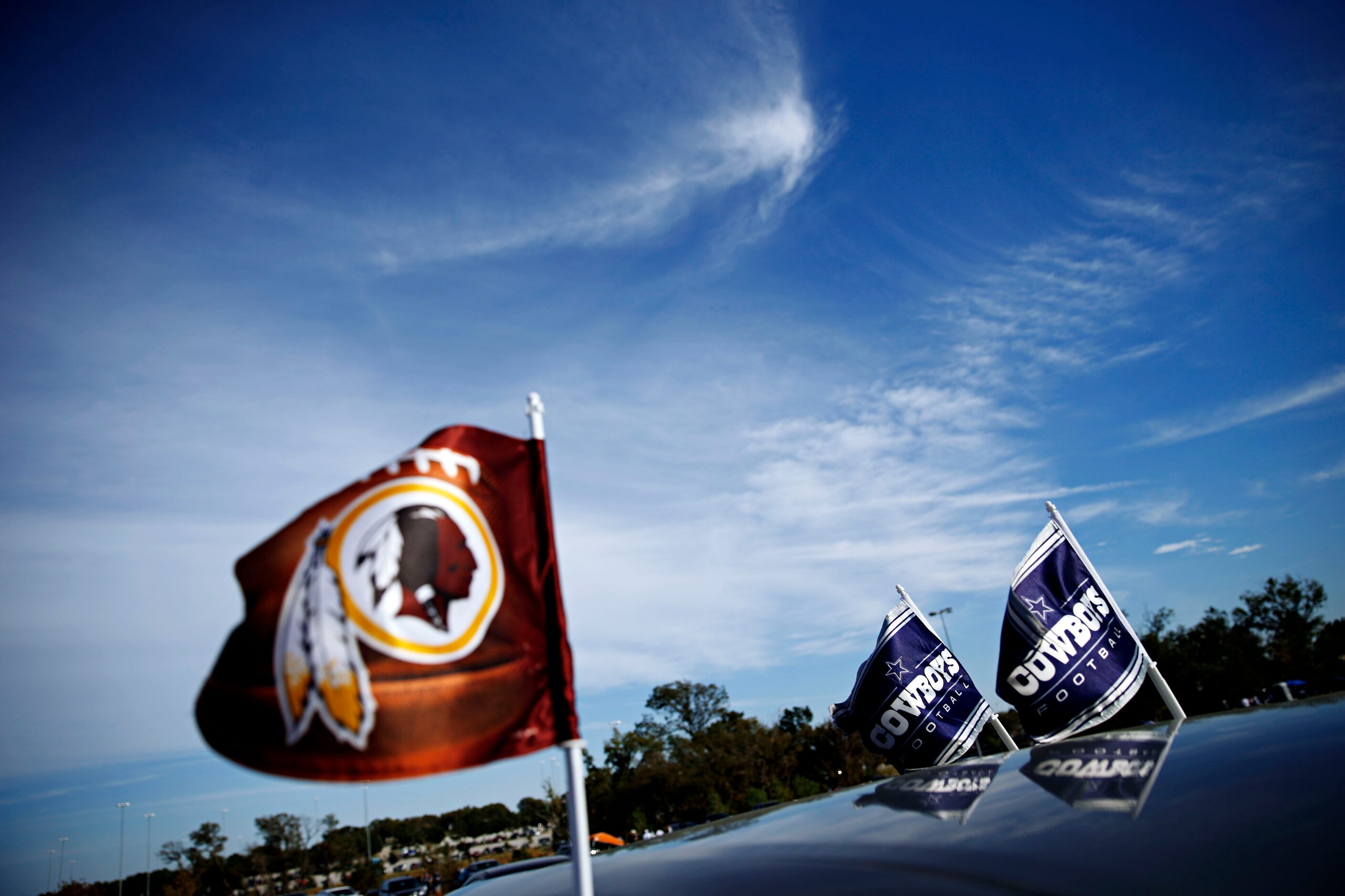 Washington Redskins and Dallas Cowboys flags fly on the same car before their game Monday,...