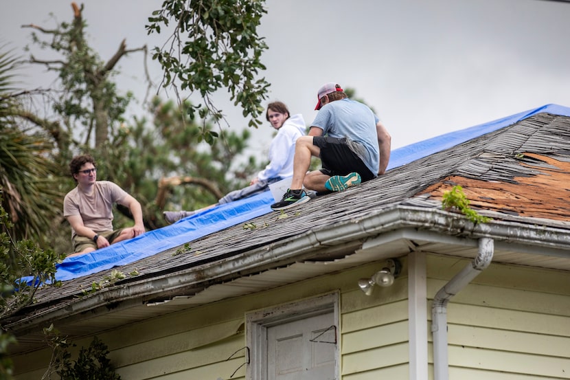 Residents repair their roof as high winds from an outer band from Tropical Storm Debby...