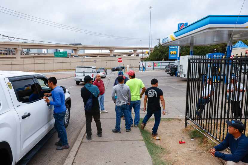 Day laborers approach a vehicle to inquire about available jobs on Thursday, Sept. 14, 2023,...