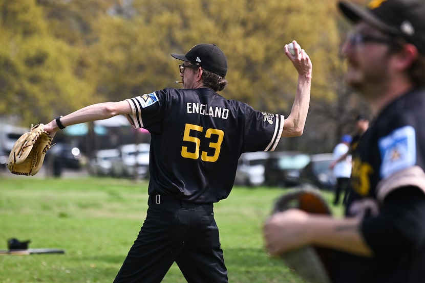 Kevin England, with a burning cigarette in his mouth, warms up by tossing a baseball...