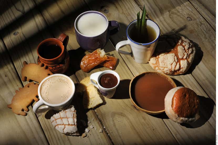 Foto de panes mexicanos, taza con café y chocolate caliente.