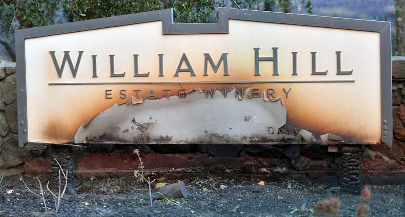 A partially burned sign is seen amidst smoldering remains at William Hill Estate Winery in...