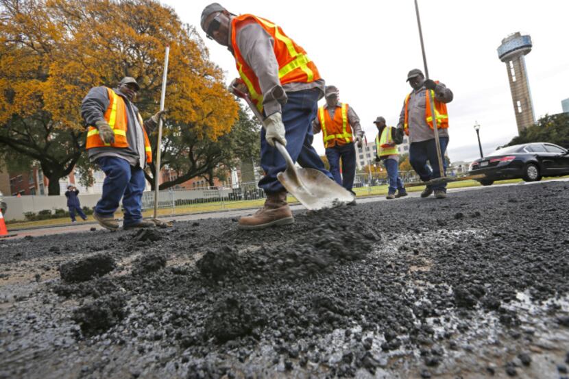 Workers focused Wednesday on repaving the asphalt on Elm Street in Dealey Plaza before...