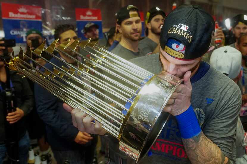 Texas Rangers catcher Jonah Heim Texas kisses the Commissioner’s Trophy as players celebrate...