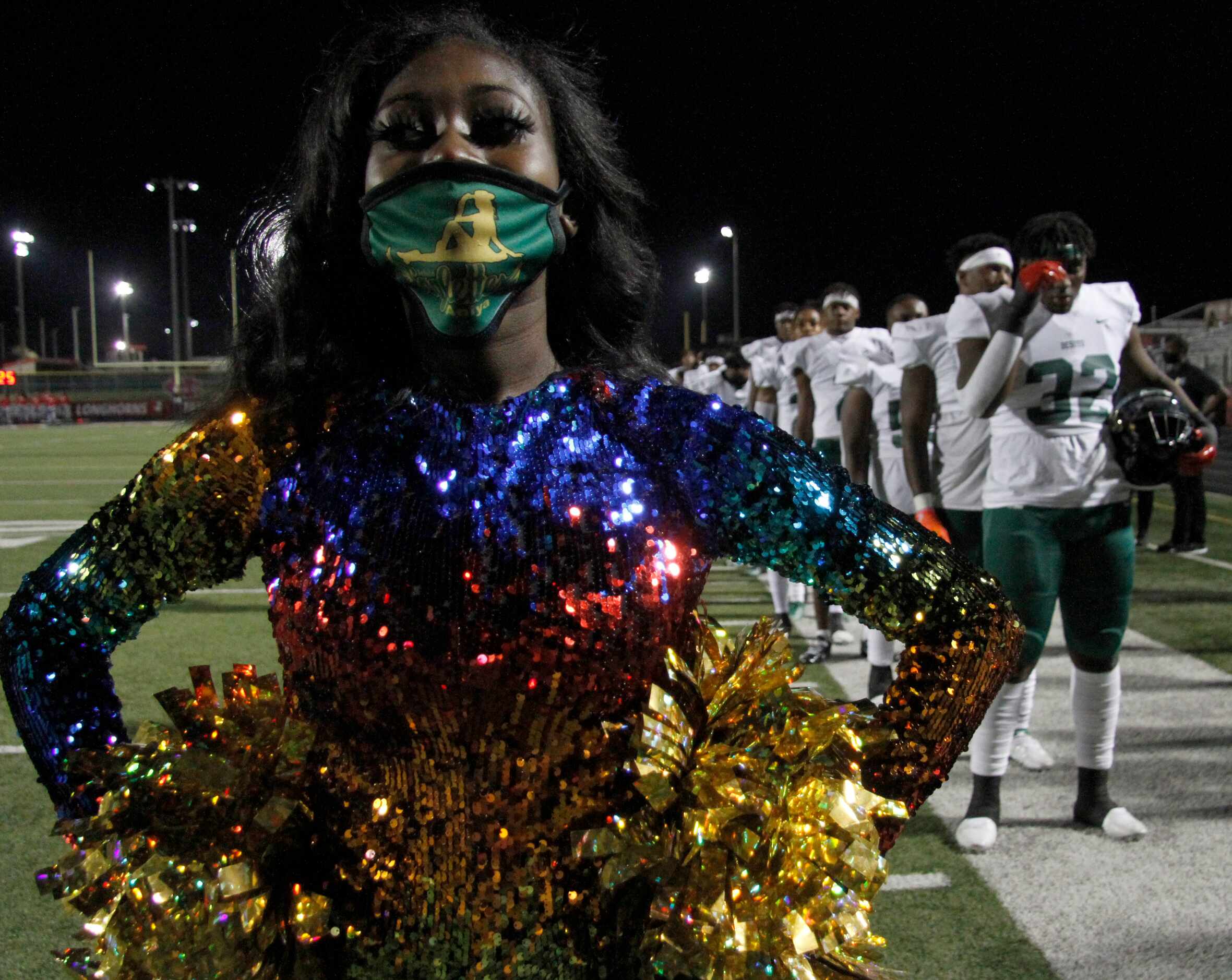 A DeSoto Eagles drill team members pauses alongside Eagles players for the playing of the...