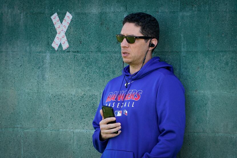 Texas Rangers general manager Jon Daniels leans against a wall in the bullpen while talking...