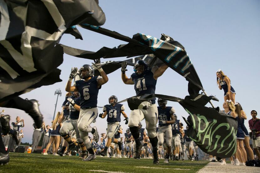 Flower Mound Jaguars players run onto the field before the high school football game between...