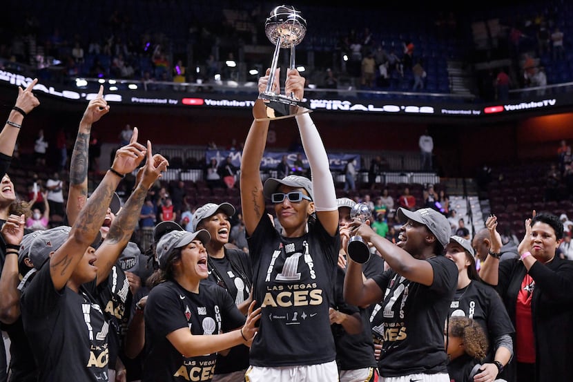 Las Vegas Aces' A'ja Wilson holds up the championship trophy as she celebrates with her team...