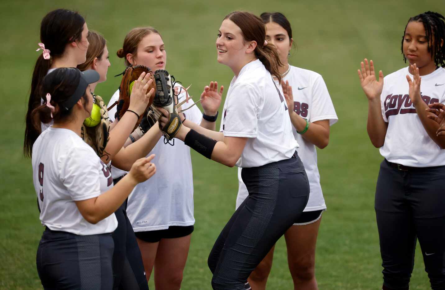 Frisco Heritage third baseman Sam Riley slaps gloves with teammates as she is introduced...