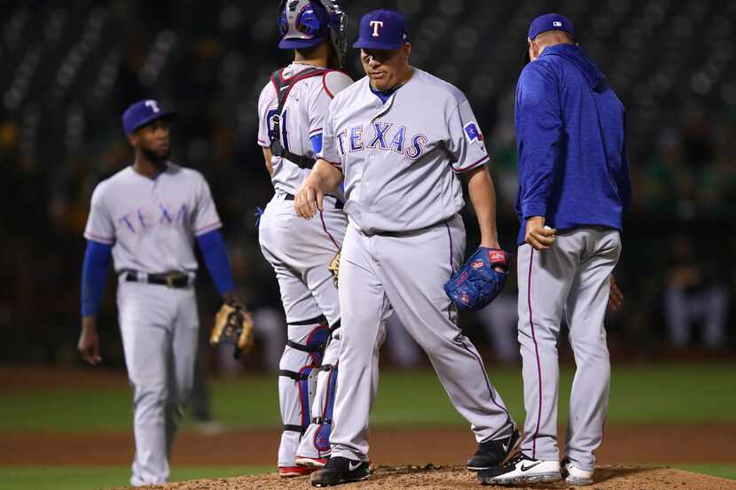 Texas Rangers' Bartolo Colon, center, walks off the mound after being relieved by manager...