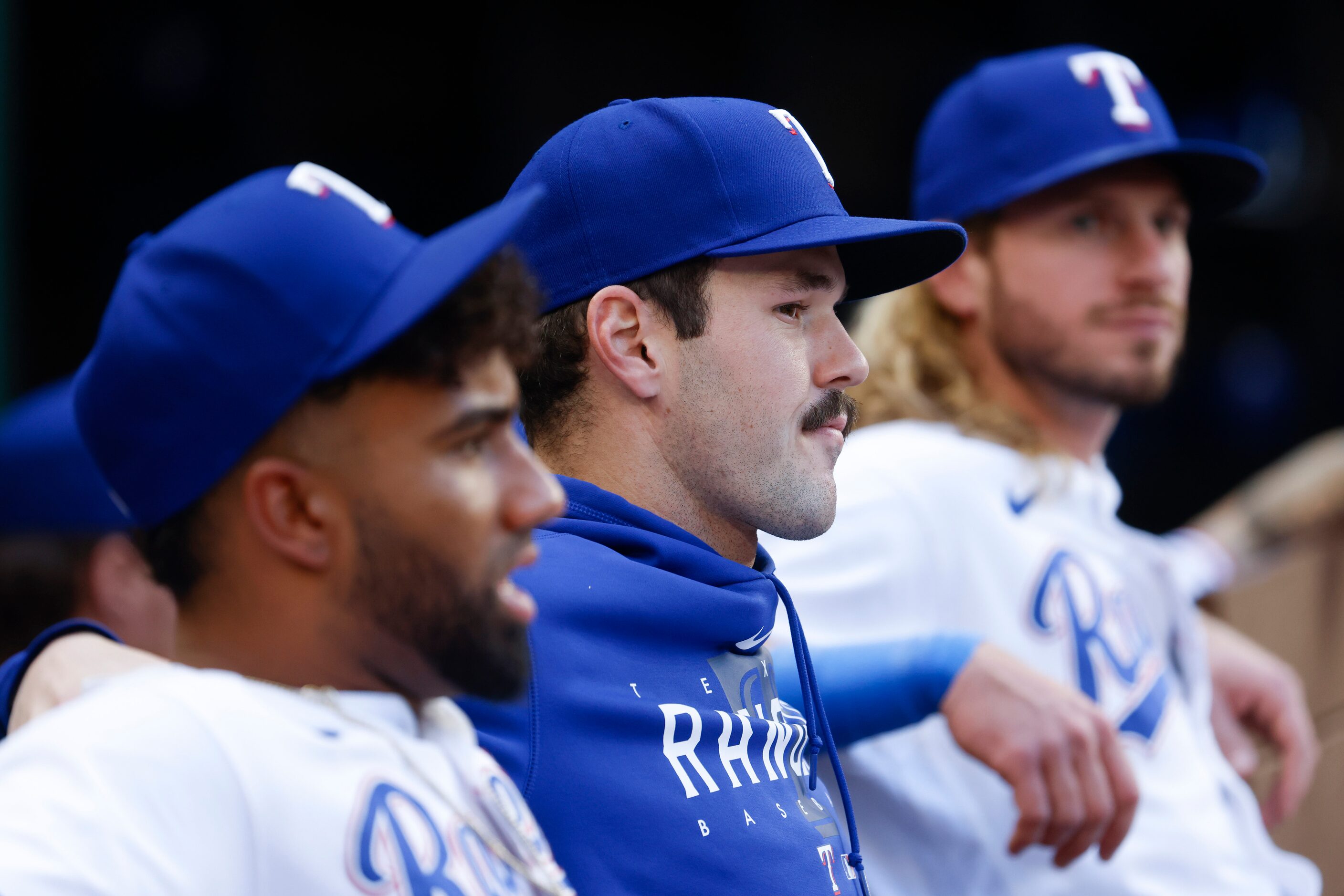 Texas Rangers starting pitcher Cole Ragans (center) sits in the dugout before a baseball...