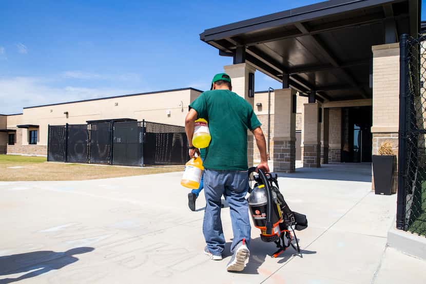 Custodian George Cox (right) carries a respirator and cleaning supplies into Jim Spradley...