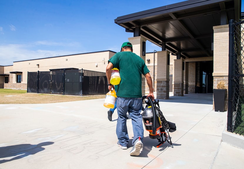 Custodian George Cox (right) carries a respirator and cleaning supplies into Jim Spradley...