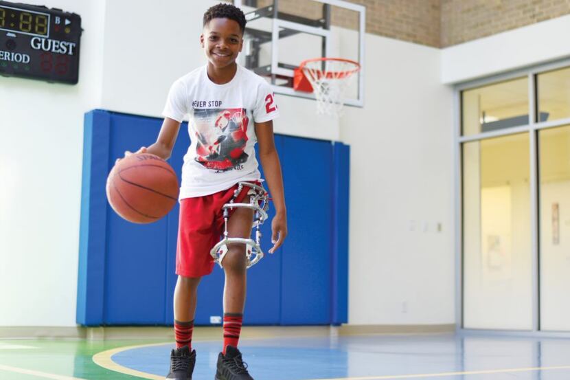 A child with a brace on his leg plays basketball in a court.