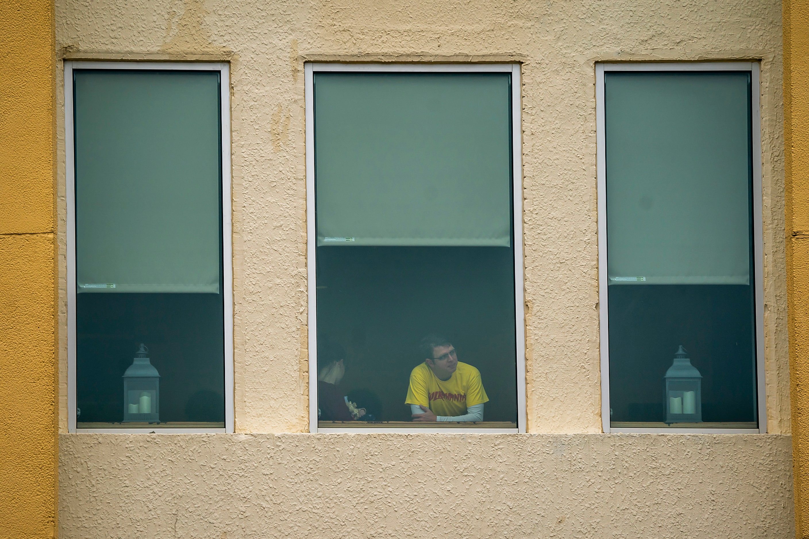 People watch from a window during The Greater Dallas Veterans Day Parade on Monday, Nov. 11,...