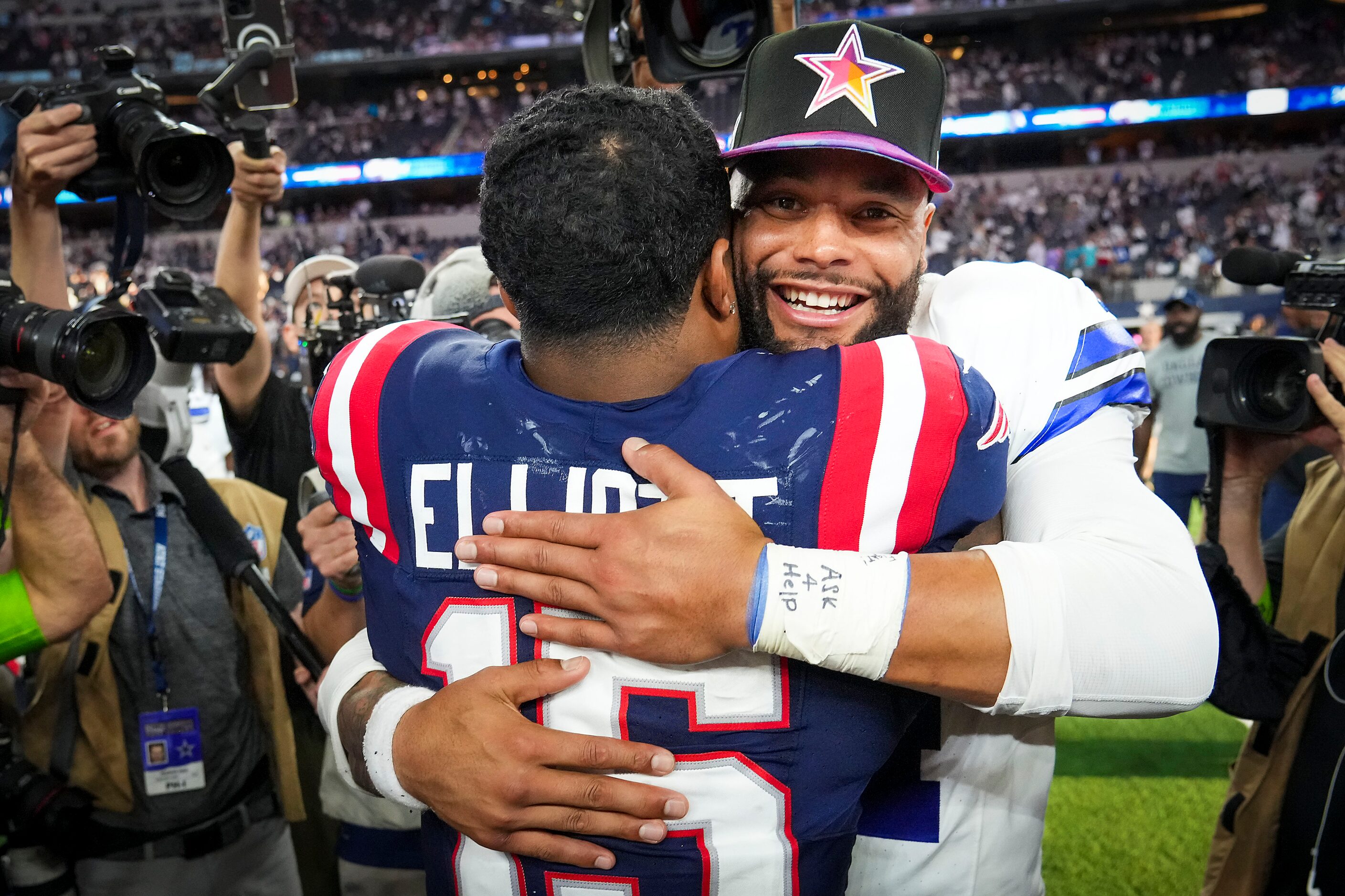 Dallas Cowboys quarterback Dak Prescott (4) hugs New England Patriots running back Ezekiel...